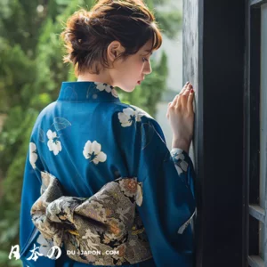 Femme en kimono bleu floral, élégante et contemporaine, dans un jardin paisible.