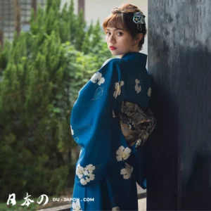 Femme en kimono bleu, élégante et sereine, dans un jardin verdoyant au Japon.