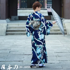 Femme en kimono bleu dans un jardin traditionnel, tenant un parasol élégant.