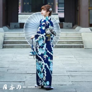 Femme en kimono navy avec ombrelle, élégance et sérénité dans un cadre traditionnel japonais.