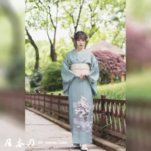 Femme en kimono vert dans un jardin paisible, symbole de grâce et tradition japonaise.