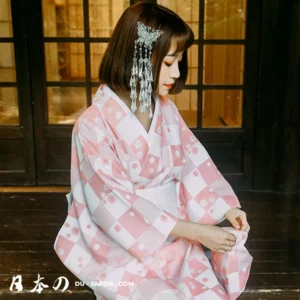 Femme en kimono rose et blanc dans un cadre japonais traditionnel.