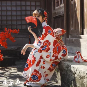 Femme en kimono rouge élégante, fan à la main, dans un cadre japonais serein.