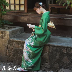 Femme en kimono vert traditionnel, moment de sérénité dans un cadre japonais paisible.