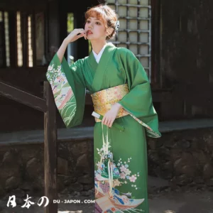 Femme en kimono vert avec obi dans un jardin traditionnel japonais.