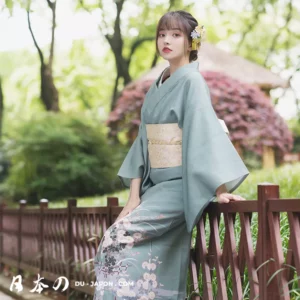 Jeune femme en kimono vert, posant dans un cadre naturel paisible et serein.