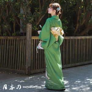 Femme en kimono vert fleuri, élégance et sérénité dans un cadre naturel.