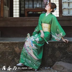 Femme en kimono vert avec obi doré, ambiance sereine et traditionnelle au Japon.