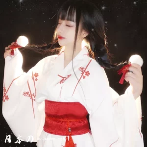 Femme en kimono blanc et rouge, expression sereine sous une lumière douce.