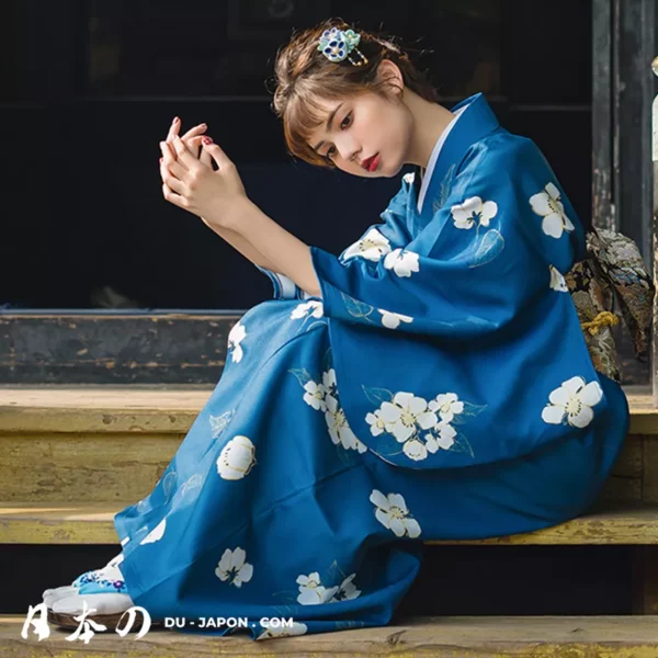 Femme en kimono bleu floral, contemplative sur des marches en bois, beauté japonaise.