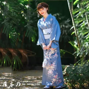 Jeune femme en kimono bleu dans un cadre naturel tropical, souriante et élégante.