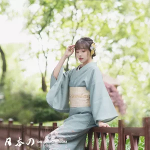 Femme en kimono bleu dans un jardin paisible, élégance et beauté traditionnelles japonaises.