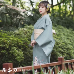 Femme en kimono traditionnel dans un jardin verdoyant, élégance naturelle et sérénité.