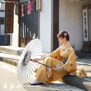 Femme en kimono jaune avec parasol sur une rue traditionnelle japonaise.