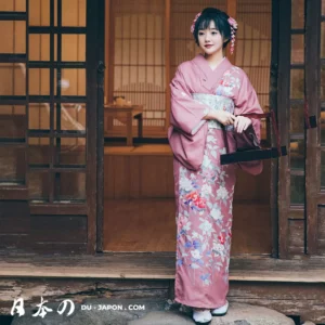 Jeune femme en kimono rose, fleurs sakura, devant une structure traditionnelle japonaise.