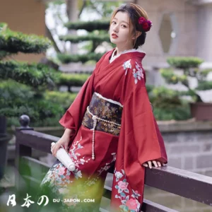 Femme en kimono rouge dans un jardin, élégance traditionnelle et sérénité authentique.