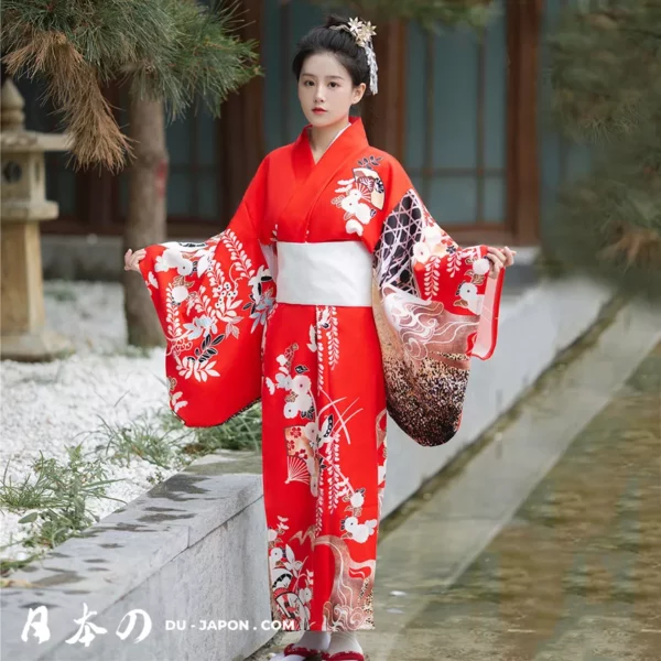 Femme en kimono rouge traditionnel dans un jardin japonais, symbole délégance et de culture.