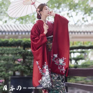 Femme en kimono rouge avec parasol dans un jardin japonais paisible.