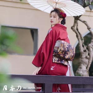 Femme en kimono rouge avec parasol, élégance traditionnelle dans un cadre naturel.