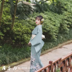 Femme en kimono vert, fleurs délicates, dans un jardin serein et verdoyant.