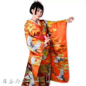 Jeune femme en kimono orange élégant avec motifs de grues, célébrant la culture japonaise.