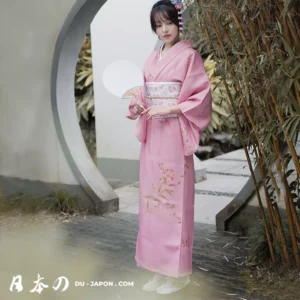 Femme en kimono rose sous un arc en pierre, entourée de verdure paisible.