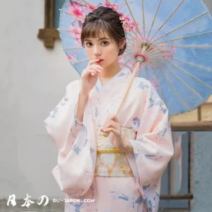 Jeune femme en kimono rose avec parasol bleu, capturant la beauté traditionnelle japonaise.