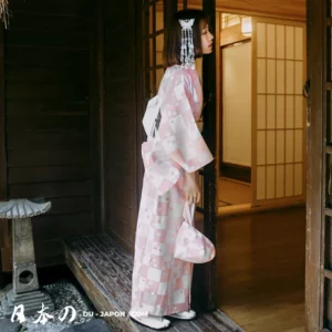 Jeune femme en kimono rose traditionnel devant une porte en bois, ambiance sereine japonaise.