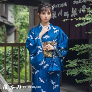 Femme en kimono bleu élégant, ornée de grues, dans un cadre japonais traditionnel.