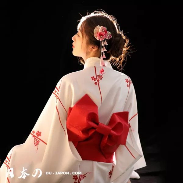 Femme en kimono blanc avec fleurs rouges et obi, élégance japonaise traditionnelle.