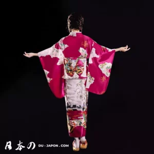 Femme en kimono rose avec motifs floraux, posant gracieusement dans un cadre traditionnel japonais.