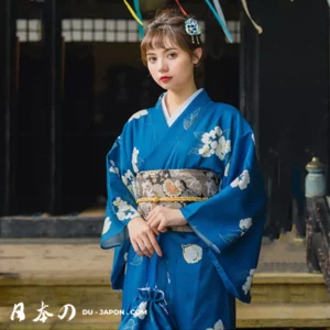 Femme en kimono bleu fleuri, élégance japonaise dans un cadre traditionnel.