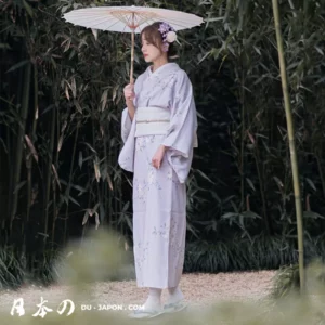 Femme en kimono lavande sous un parasol, entourée de bambous, évoque sérénité.