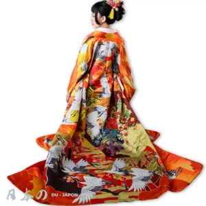 Femme en kimono orange élégant avec motifs de grues et fleurs, symbole de la culture japonaise.