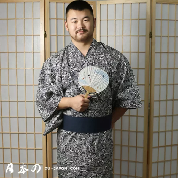 Homme en yukata traditionnel bleu, tenant un éventail, dans un décor japonais authentique.