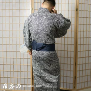 Homme en yukata traditionnel sombre avec obi navy, devant un shoji japonais.