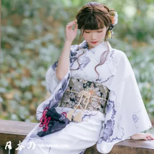 Femme en kimono blanc élégant dans un jardin, moment de réflexion et de sérénité.