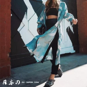 Femme en kimono moderne, style urbain, devant un mur artistique bleu et blanc.