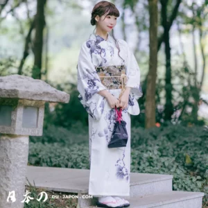 Femme en kimono blanc dans un jardin japonais paisible, alliant tradition et modernité.