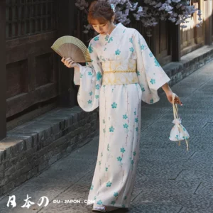 Femme en kimono blanc avec motifs floraux turquoise et éventail traditionnel.