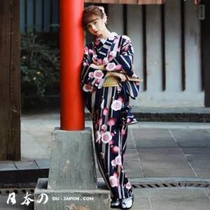 Femme en kimono bleu fleuri, posant avec grâce dans une cour japonaise traditionnelle.