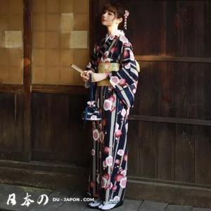 Femme en kimono bleu fleuri tenant un éventail, dans un cadre traditionnel japonais.