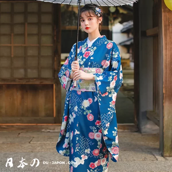 Femme en kimono bleu floral, tenant un parasol, dans un cadre japonais traditionnel.