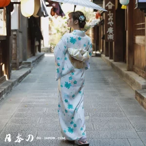 Femme en kimono fleuri avec parasol dans une rue traditionnelle japonaise.