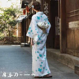 Femme en kimono floral turquoise dans un jardin tranquille au Japon.