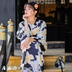 Femme en kimono floral assise, sous une architecture japonaise traditionnelle, élégance et sérénité.