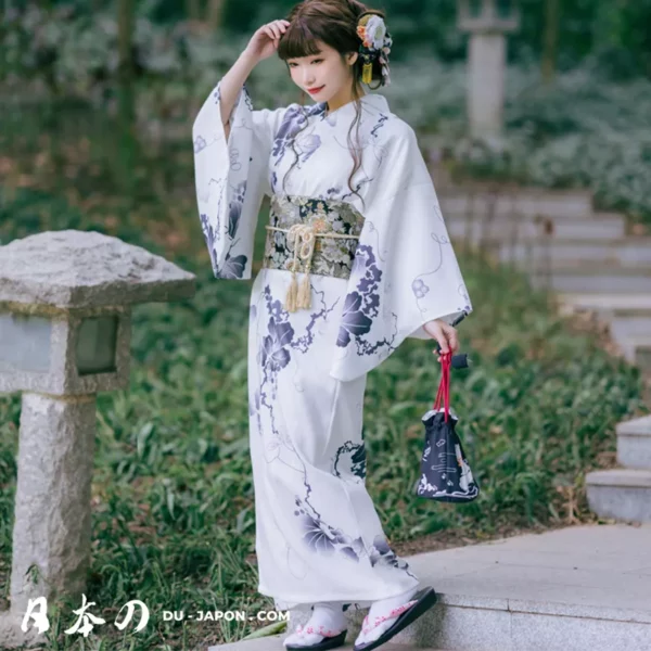 Femme en kimono blanc fleuri dans un jardin japonais, alliant tradition et modernité.