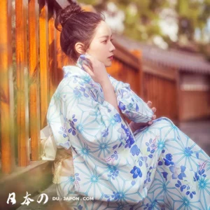 Femme en kimono blanc dans un jardin japonais, illuminée par la lumière douce du soleil.