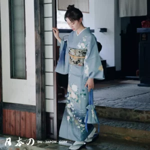 Femme en kimono bleu, élégance traditionnelle japonaise, devant une maison traditionnelle.