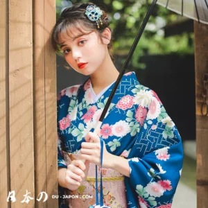 Femme en kimono bleu à fleurs, portant un parapluie, dans un cadre japonais serein.